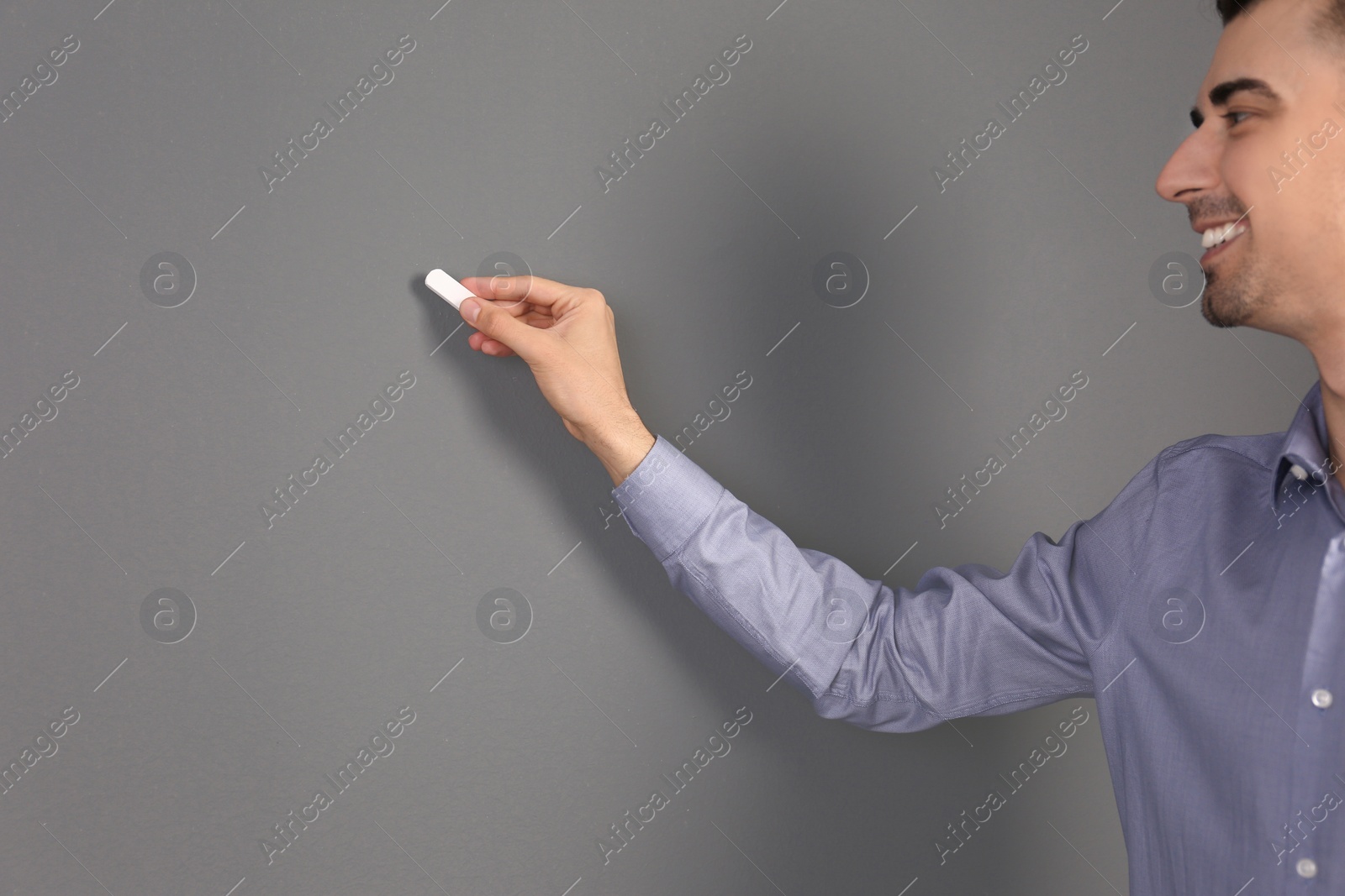 Photo of Young male teacher with chalk on grey background