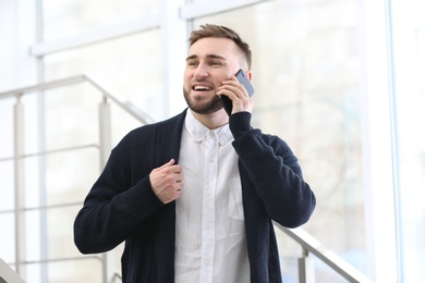 Photo of Portrait of confident young man with mobile phone on stairs