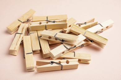 Photo of Pile of wooden clothespins on light background, closeup