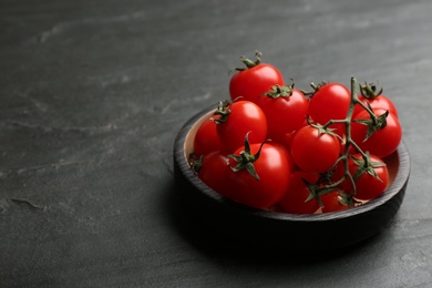 Photo of Fresh ripe cherry tomatoes on black table. Space for text