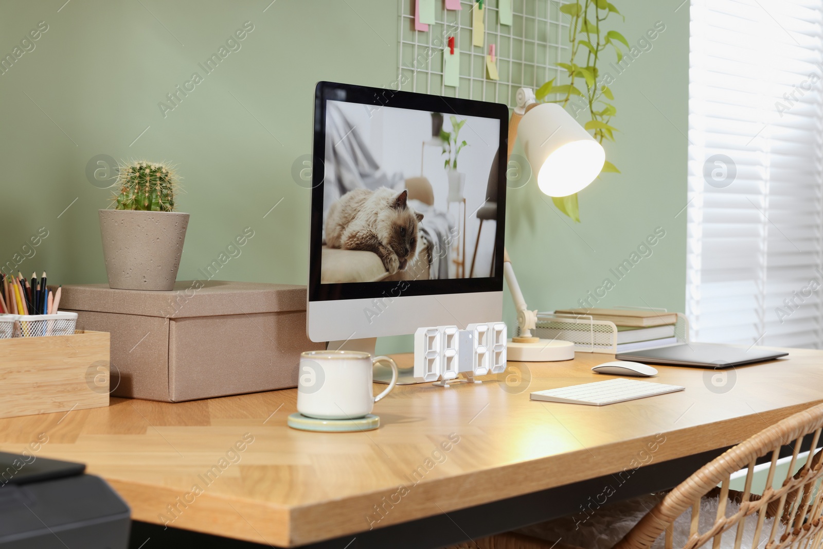 Photo of Stylish workplace with computer, laptop and lamp near olive wall at home