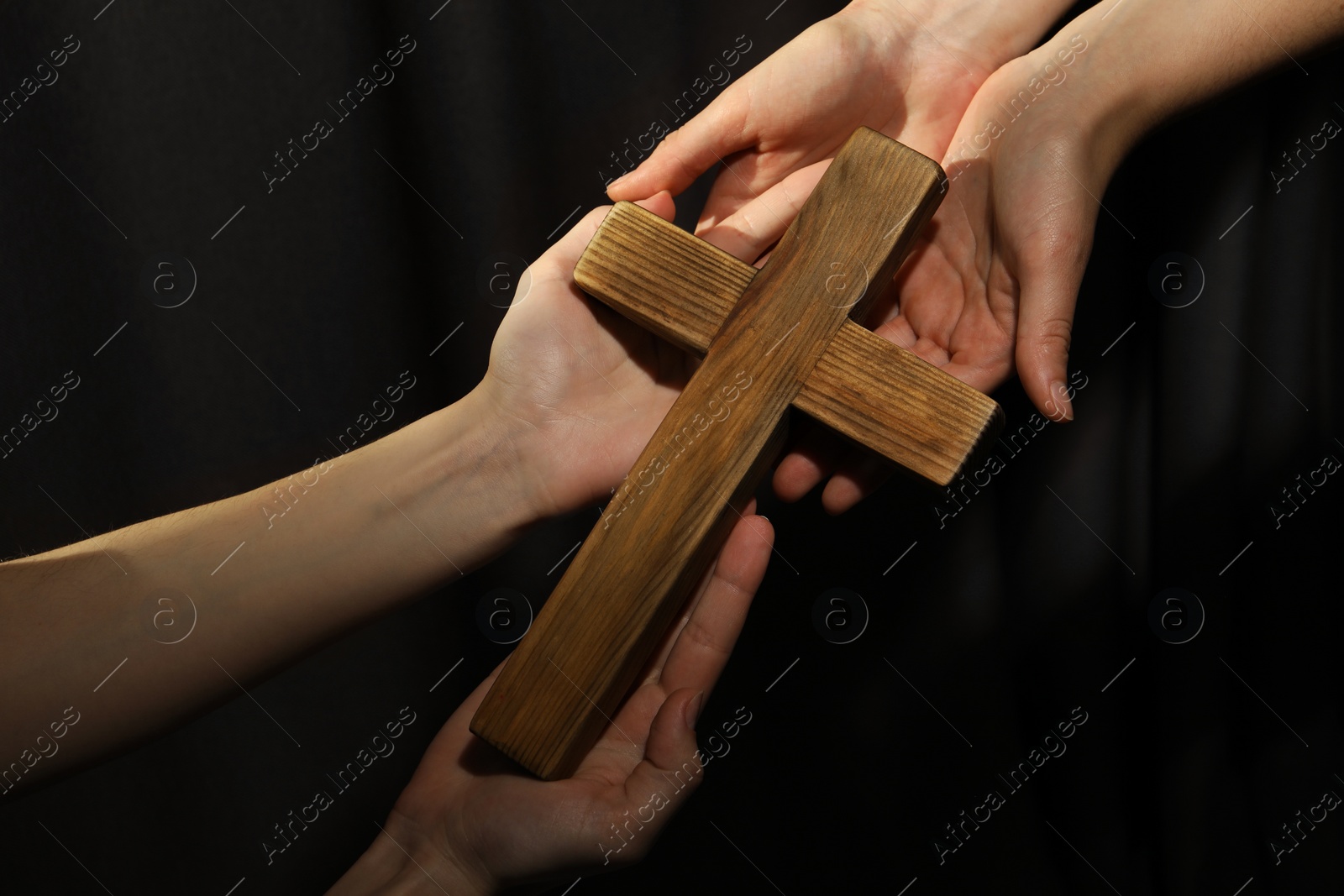 Photo of Easter - celebration of Jesus resurrection. Women holding wooden cross on dark background, closeup