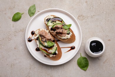 Delicious bruschettas with balsamic vinegar and toppings on light textured table, flat lay