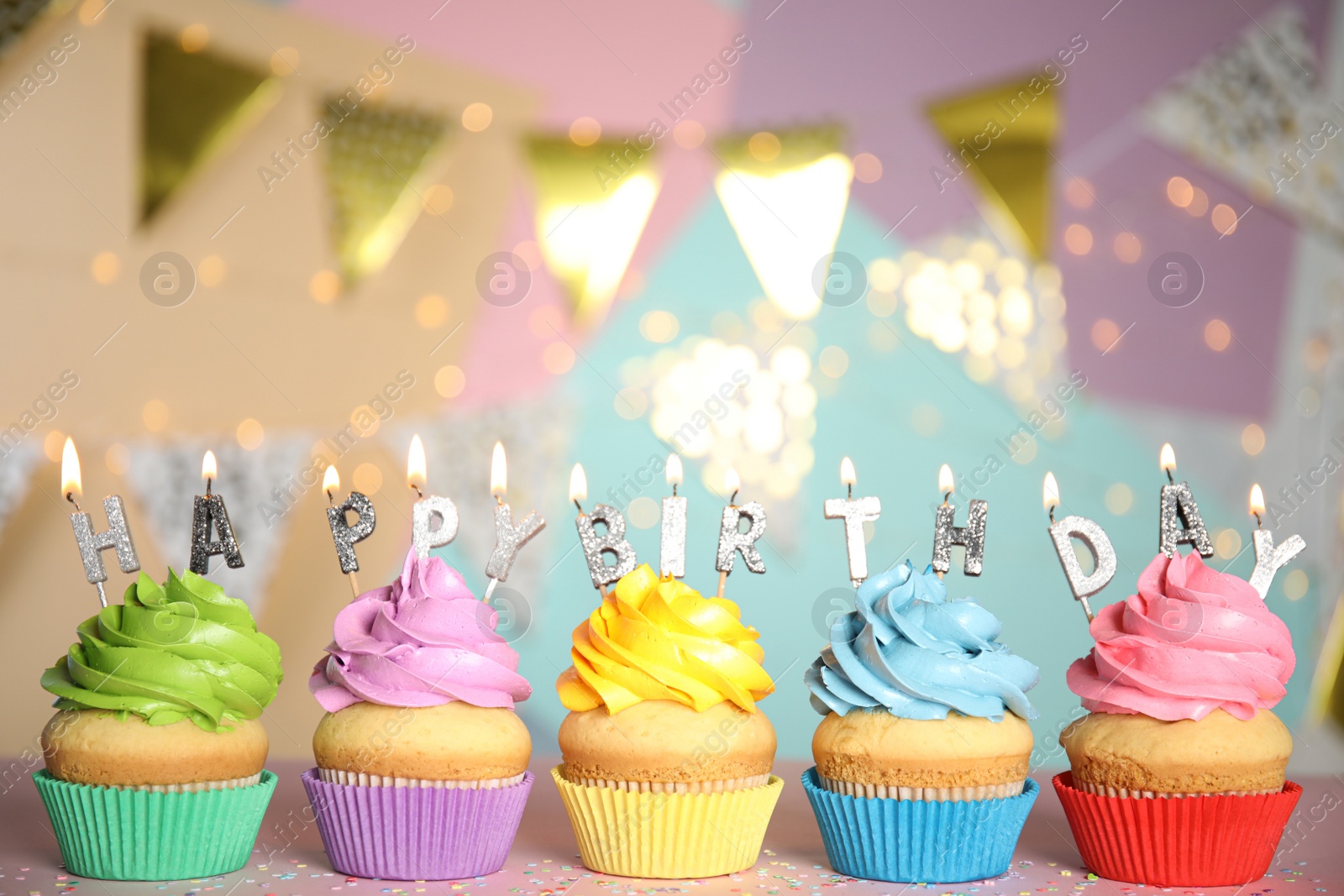 Photo of Birthday cupcakes with burning candles on pink table