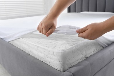 Photo of Woman covering mattress with protector indoors, closeup