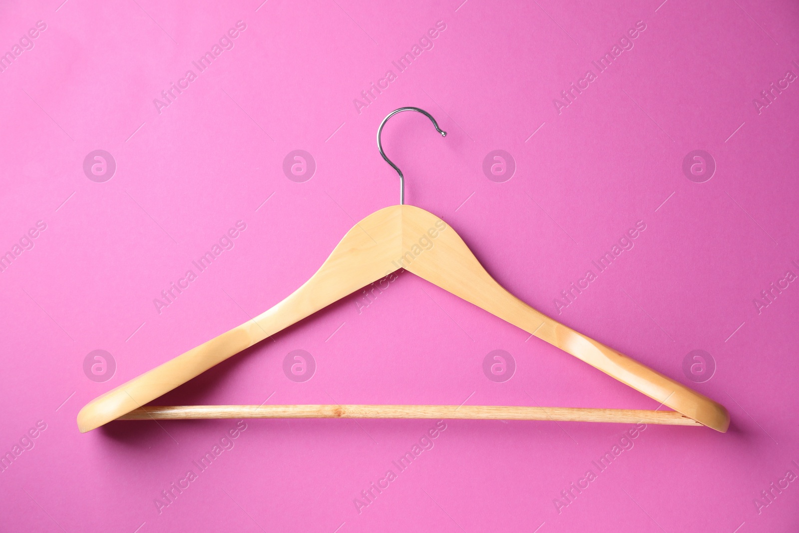 Photo of Empty wooden hanger on bright pink background, top view