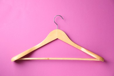 Empty wooden hanger on bright pink background, top view