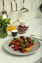 Photo of Delicious cottage cheese pancakes with fresh berries and mint on white countertop