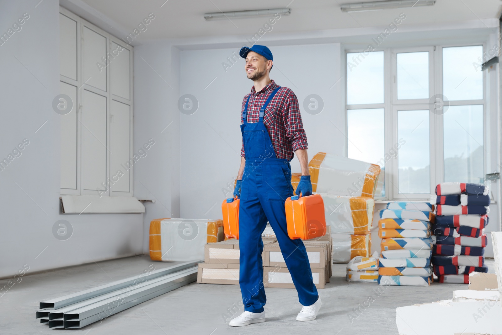 Photo of Construction worker carrying canisters in room prepared for renovation