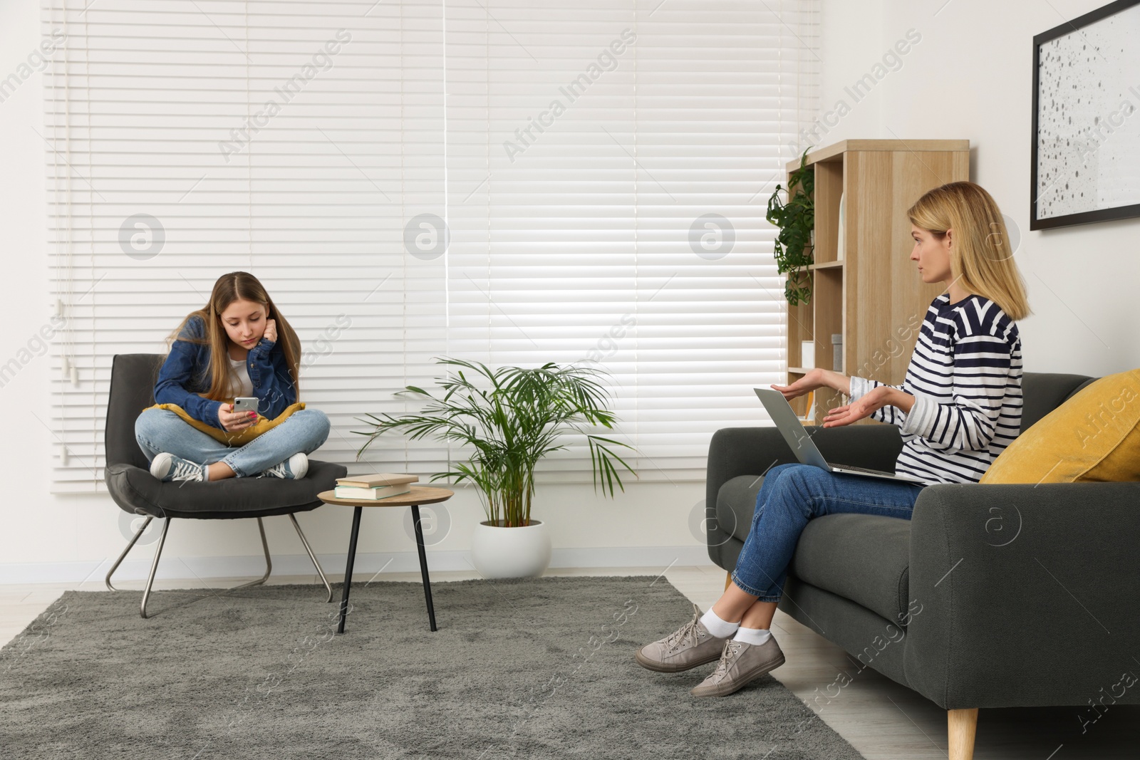 Photo of Teenage daughter with smartphone ignoring her mother at home