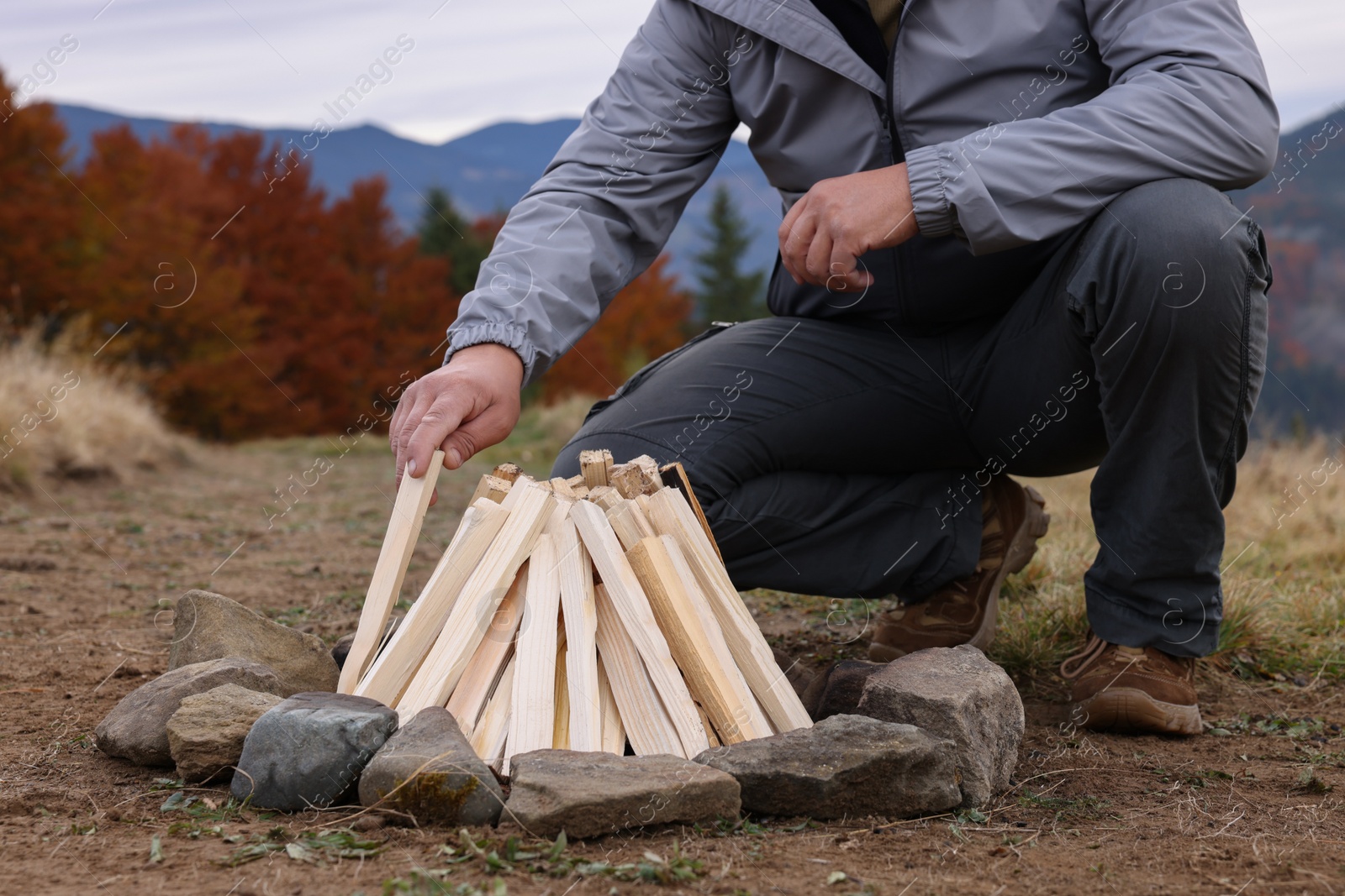 Photo of Man making bonfire in mountains, closeup. Camping season