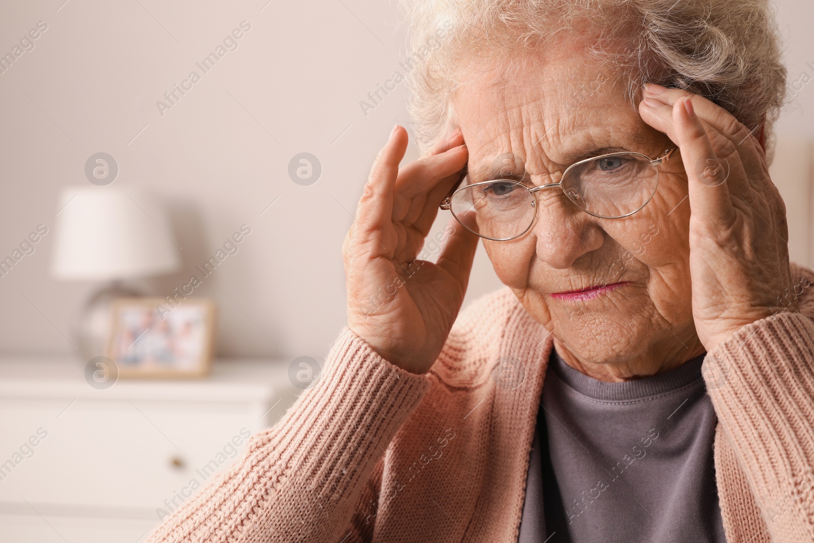 Photo of Senior woman with headache in room at home