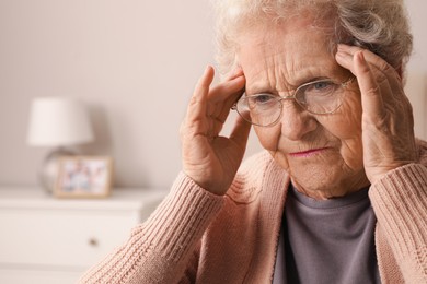 Photo of Senior woman with headache in room at home