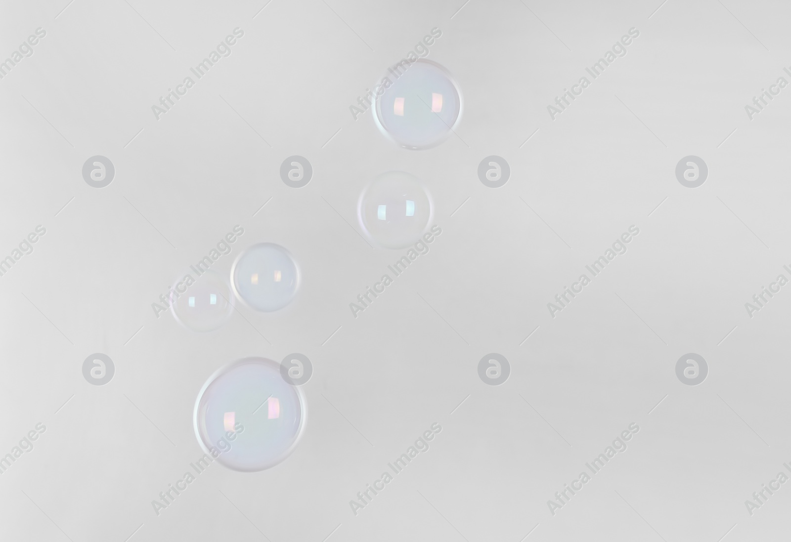 Photo of Beautiful translucent soap bubbles on light background. Space for text