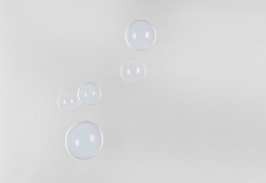 Beautiful translucent soap bubbles on light background. Space for text