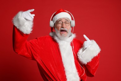 Merry Christmas. Santa Claus in headphones listening to music on red background