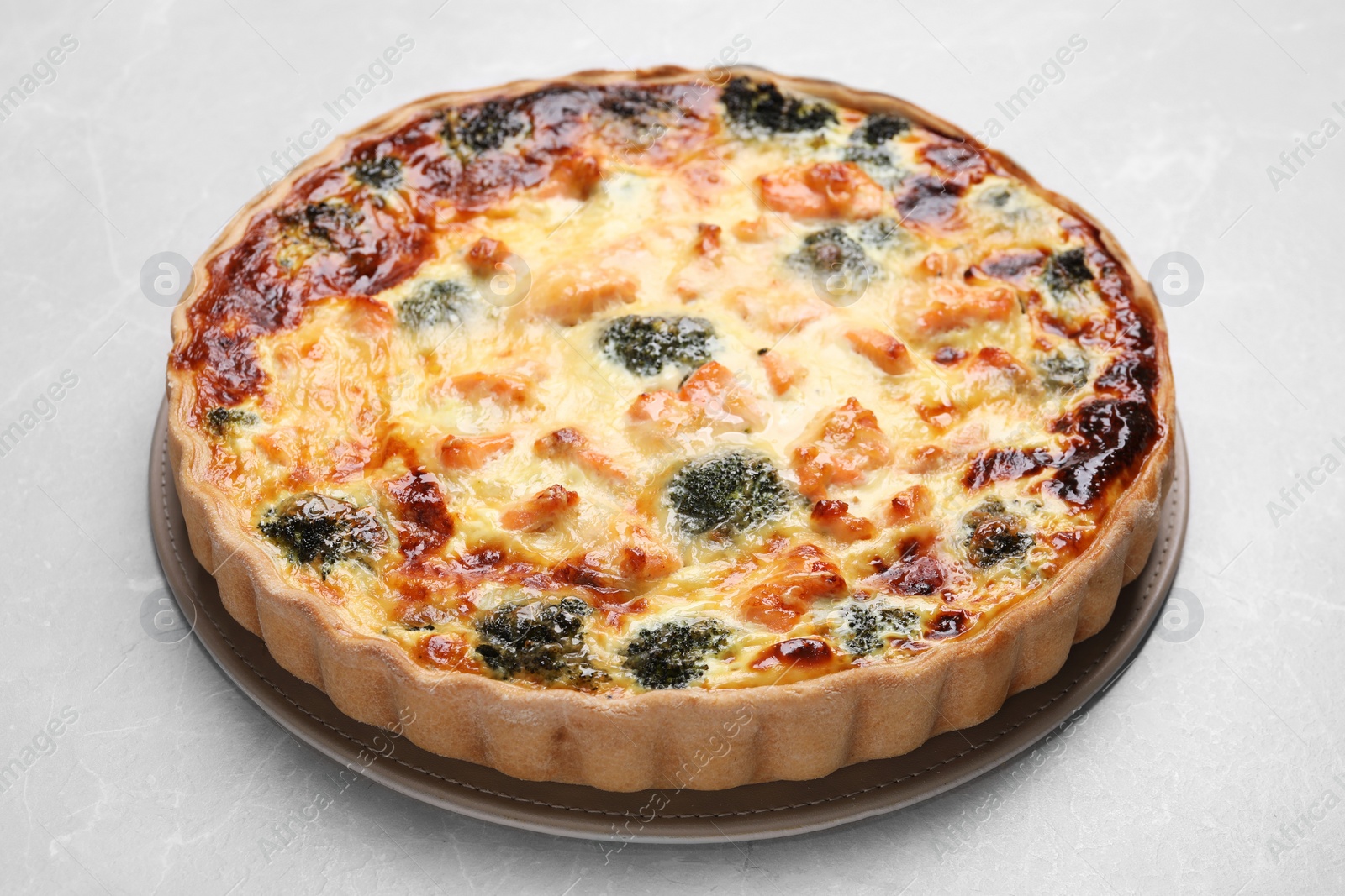 Photo of Delicious homemade quiche with salmon and broccoli on light gray table