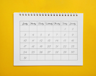 Photo of Paper calendar on yellow background, top view