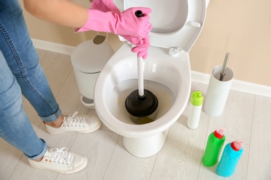 Photo of Woman cleaning toilet bowl in bathroom, closeup