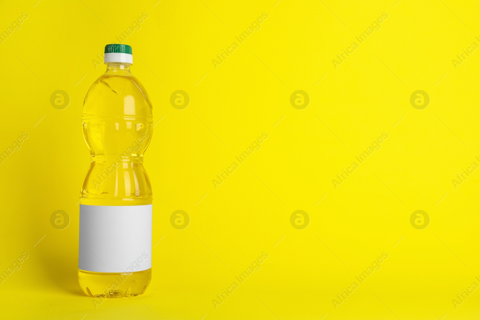 Photo of Bottle of cooking oil on yellow background. Space for text