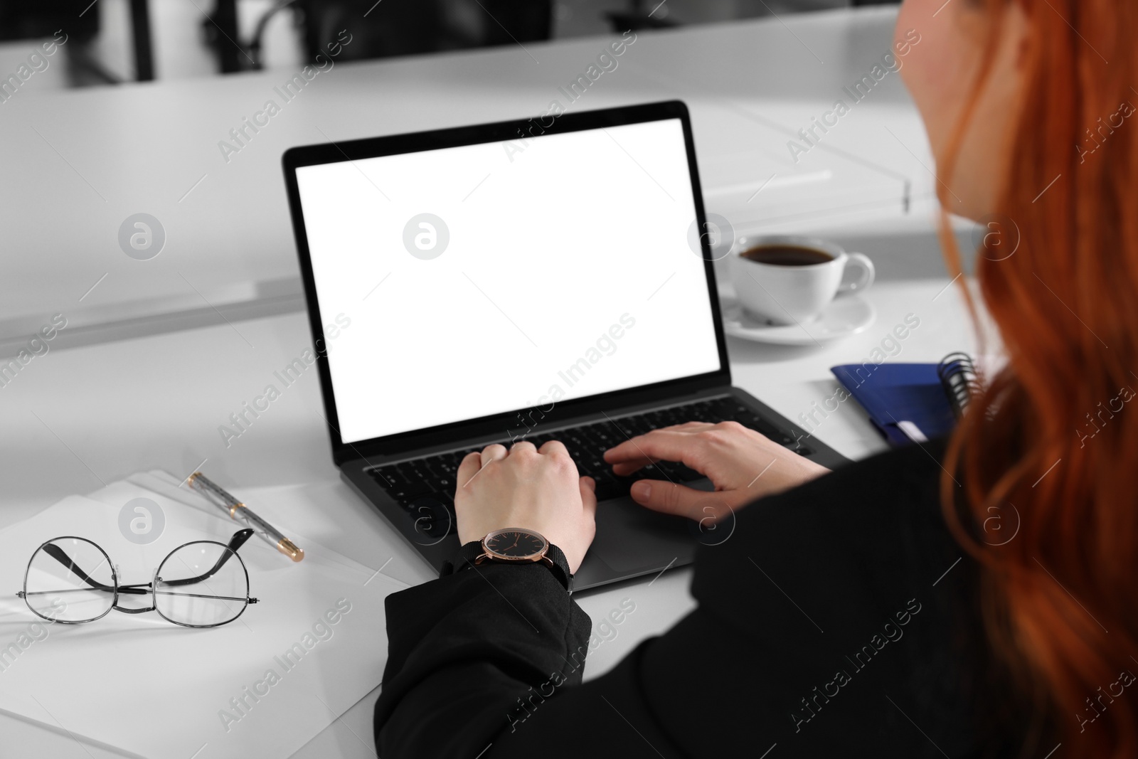 Photo of Woman working with laptop at white desk indoors, closeup