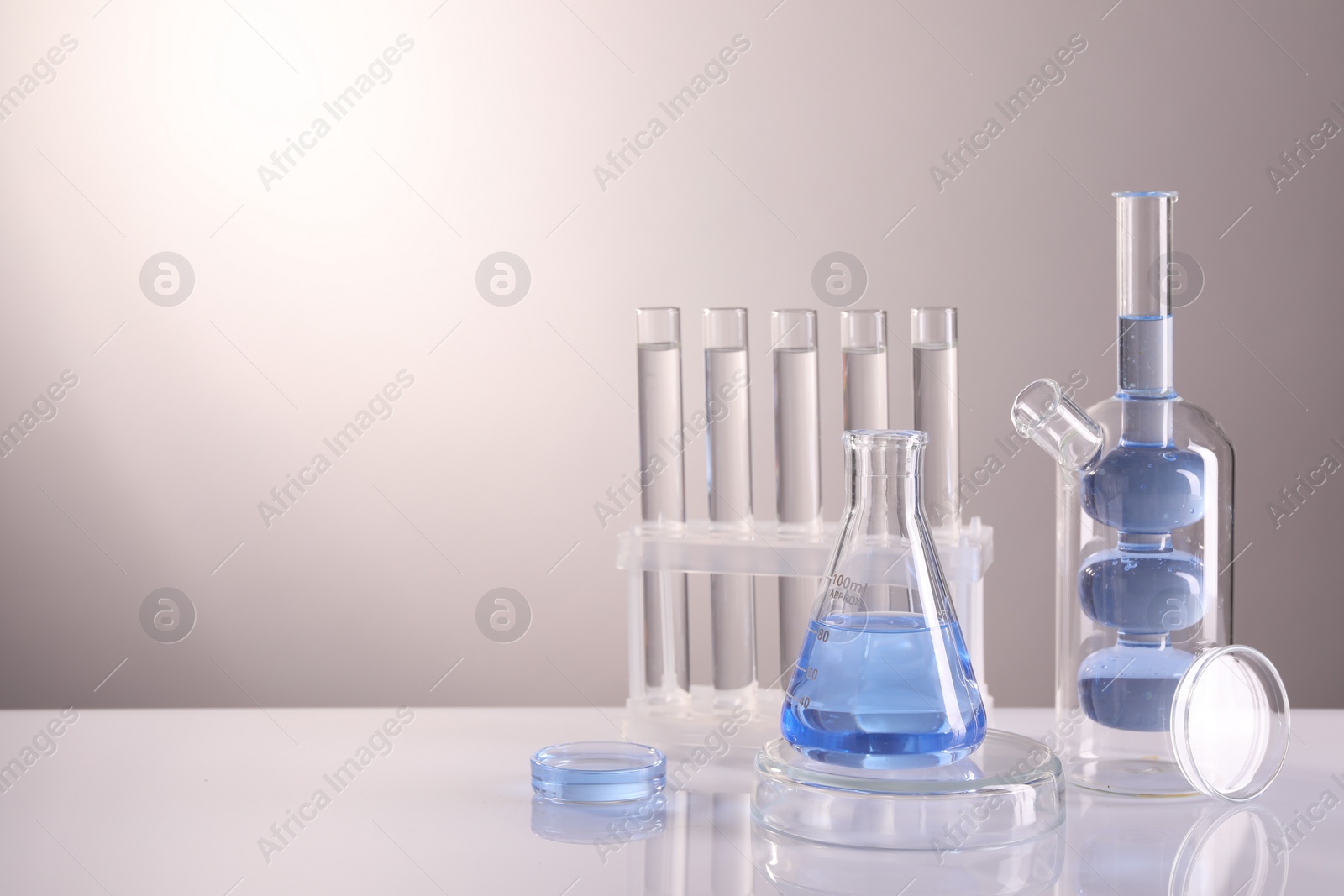 Photo of Laboratory analysis. Different glassware on table against light background, space for text