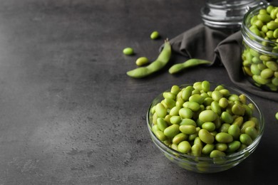 Bowl of delicious edamame beans on grey table, space for text
