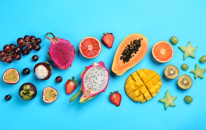 Photo of Many different delicious exotic fruits on light blue background, flat lay