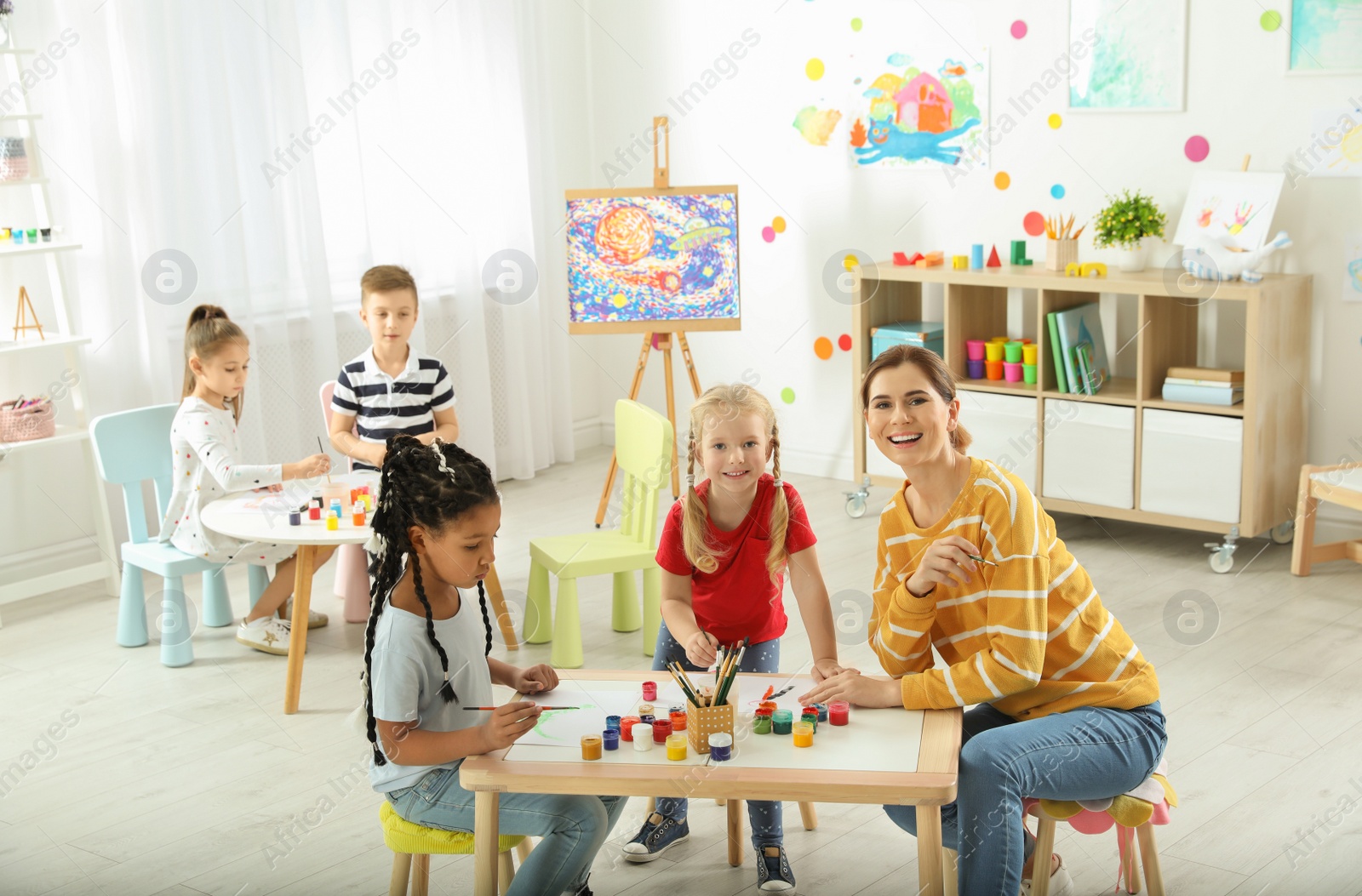 Photo of Children with female teacher at painting lesson indoors