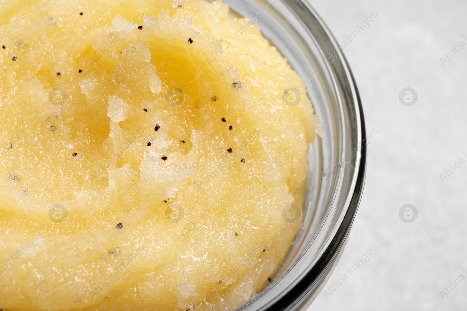 Photo of Body scrub in glass jar on light grey background, closeup