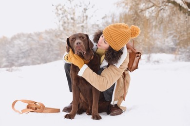 Woman with adorable Labrador Retriever dog in snowy park