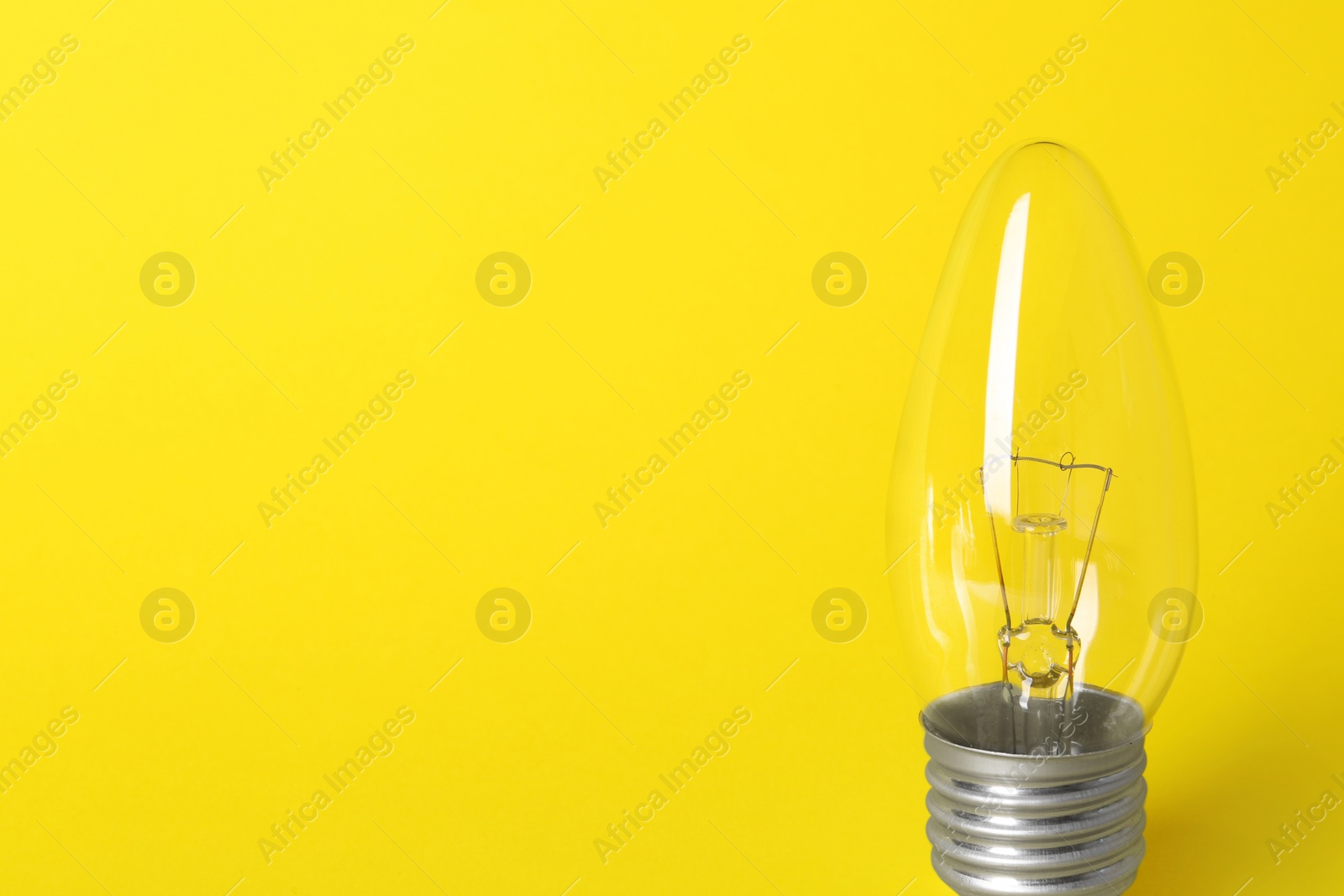 Photo of New modern lamp bulb on yellow background, space for text