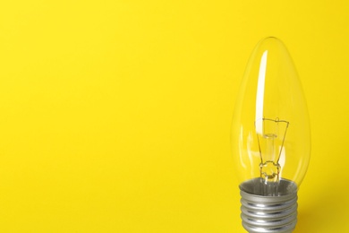 Photo of New modern lamp bulb on yellow background, space for text
