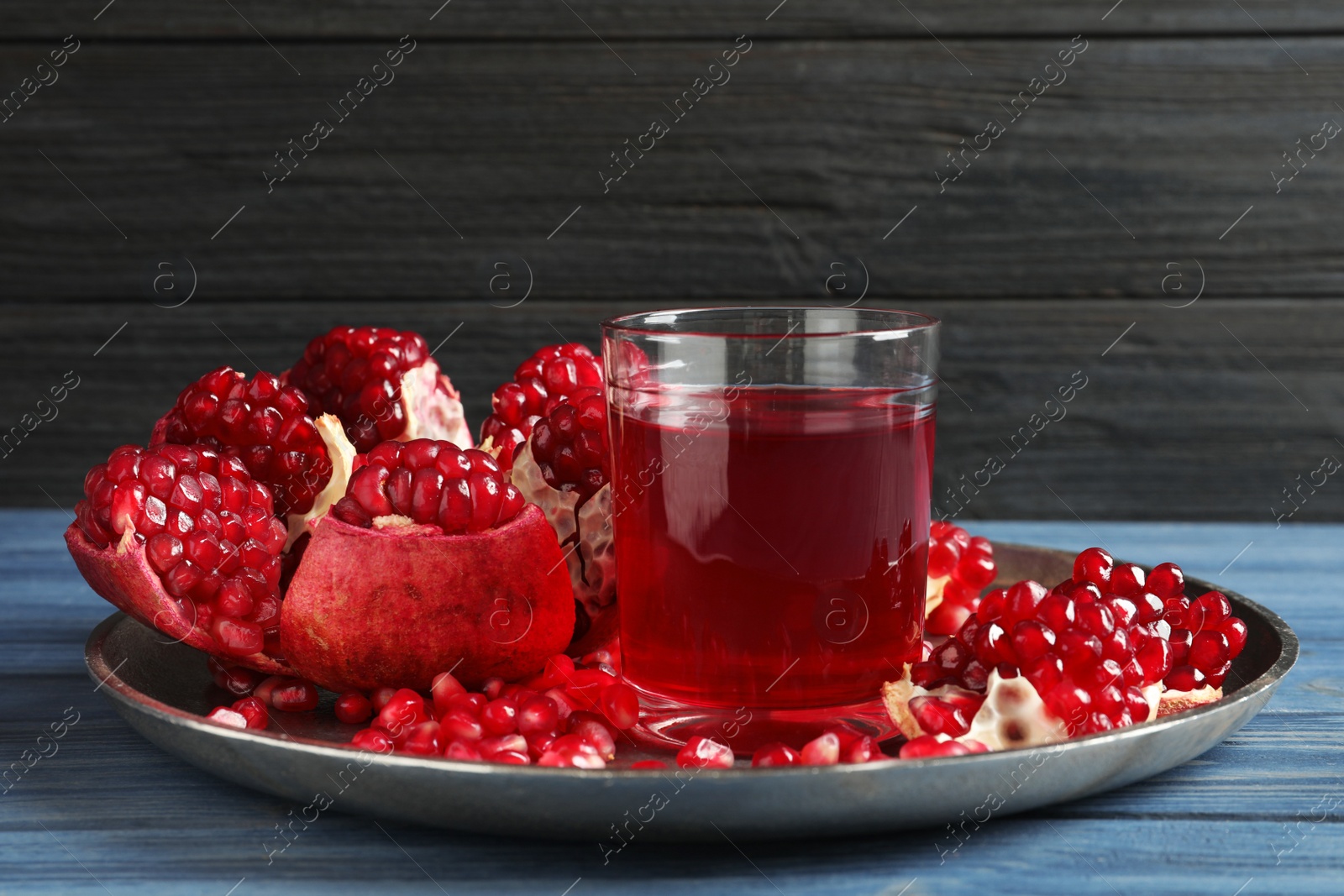 Photo of Tray with glass of pomegranate juice and fresh fruits on table against wooden background