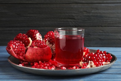 Photo of Tray with glass of pomegranate juice and fresh fruits on table against wooden background