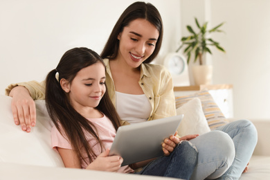 Photo of Mother and daughter reading E-book together at home