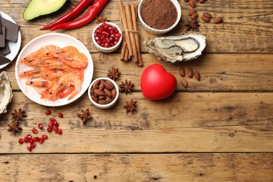 Natural aphrodisiac. Different food products and heart model on wooden table, flat lay. Space for text