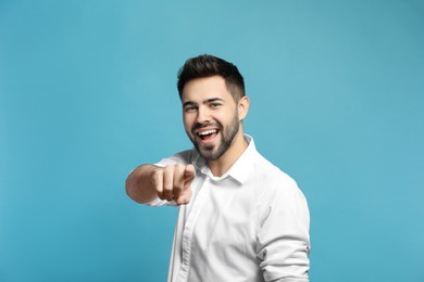 Young man laughing on light blue background. Funny joke