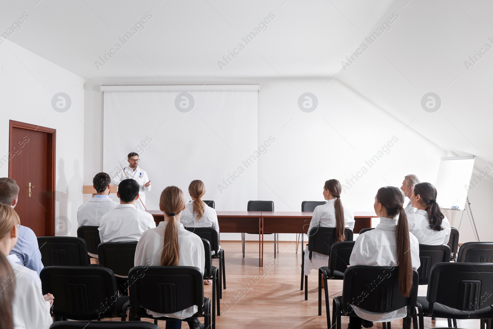 Photo of Doctor giving lecture in conference room with projection screen