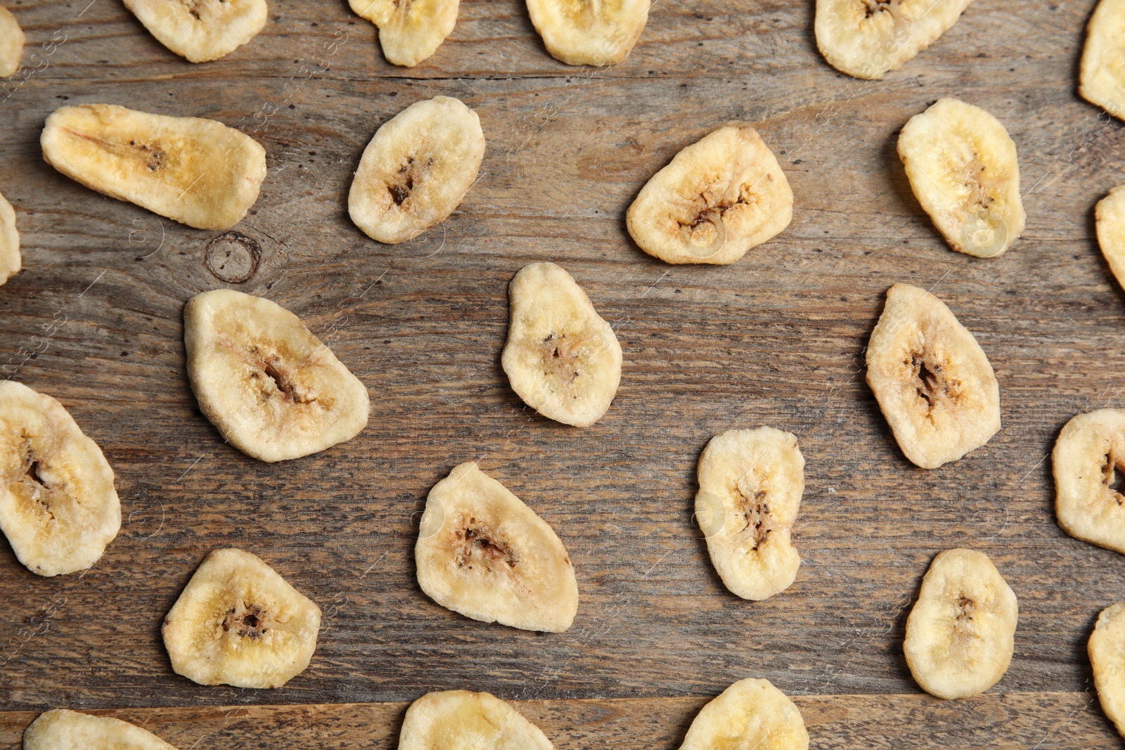 Photo of Flat lay composition with banana slices on wooden table. Dried fruit as healthy snack