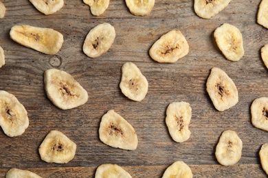 Flat lay composition with banana slices on wooden table. Dried fruit as healthy snack