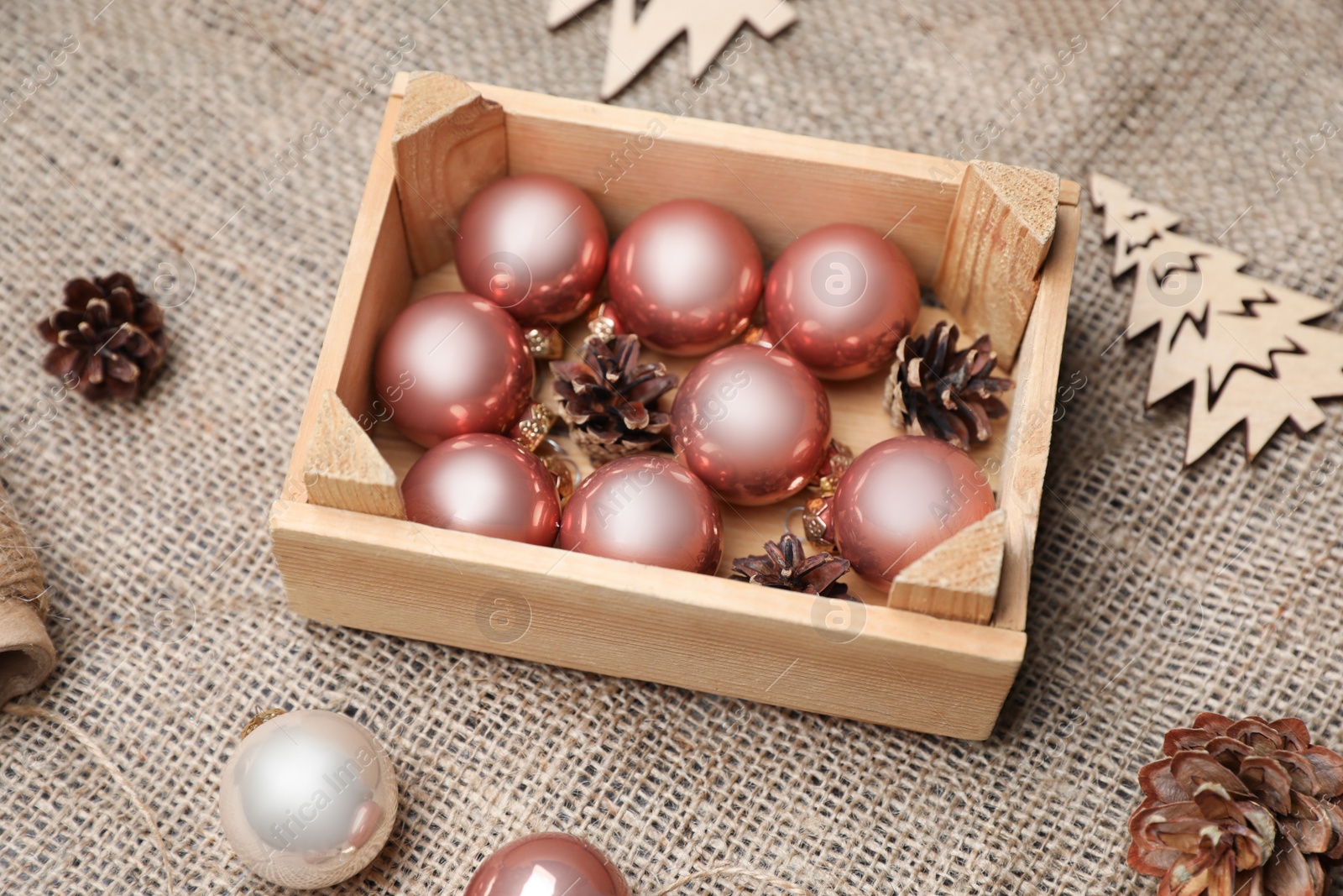 Photo of Composition with beautiful Christmas baubles and wooden crate on sacking