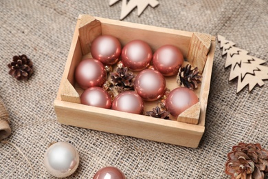 Photo of Composition with beautiful Christmas baubles and wooden crate on sacking