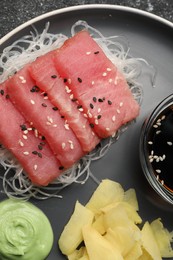 Photo of Tasty sashimi (pieces of fresh raw tuna), glass noodles, wasabi sauce and ginger slices on plate, closeup