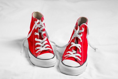 Photo of Pair of new stylish red sneakers on white fabric