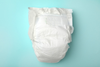 Photo of Baby diaper on turquoise background, top view