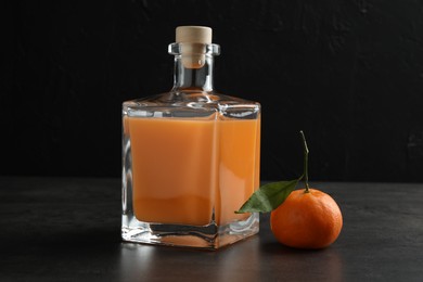 Delicious tangerine liqueur in glass bottle and fresh fruit on grey table