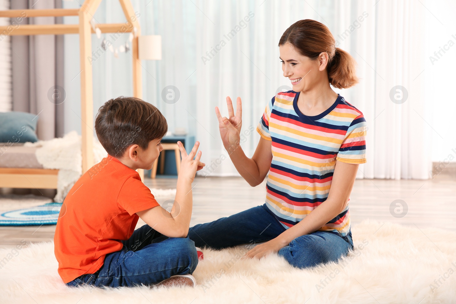 Photo of Hearing impaired mother and her child talking with help of sign language indoors