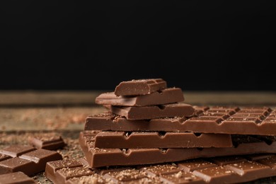 Photo of Pieces of tasty chocolate on wooden table