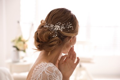 Young bride with elegant wedding hairstyle in room